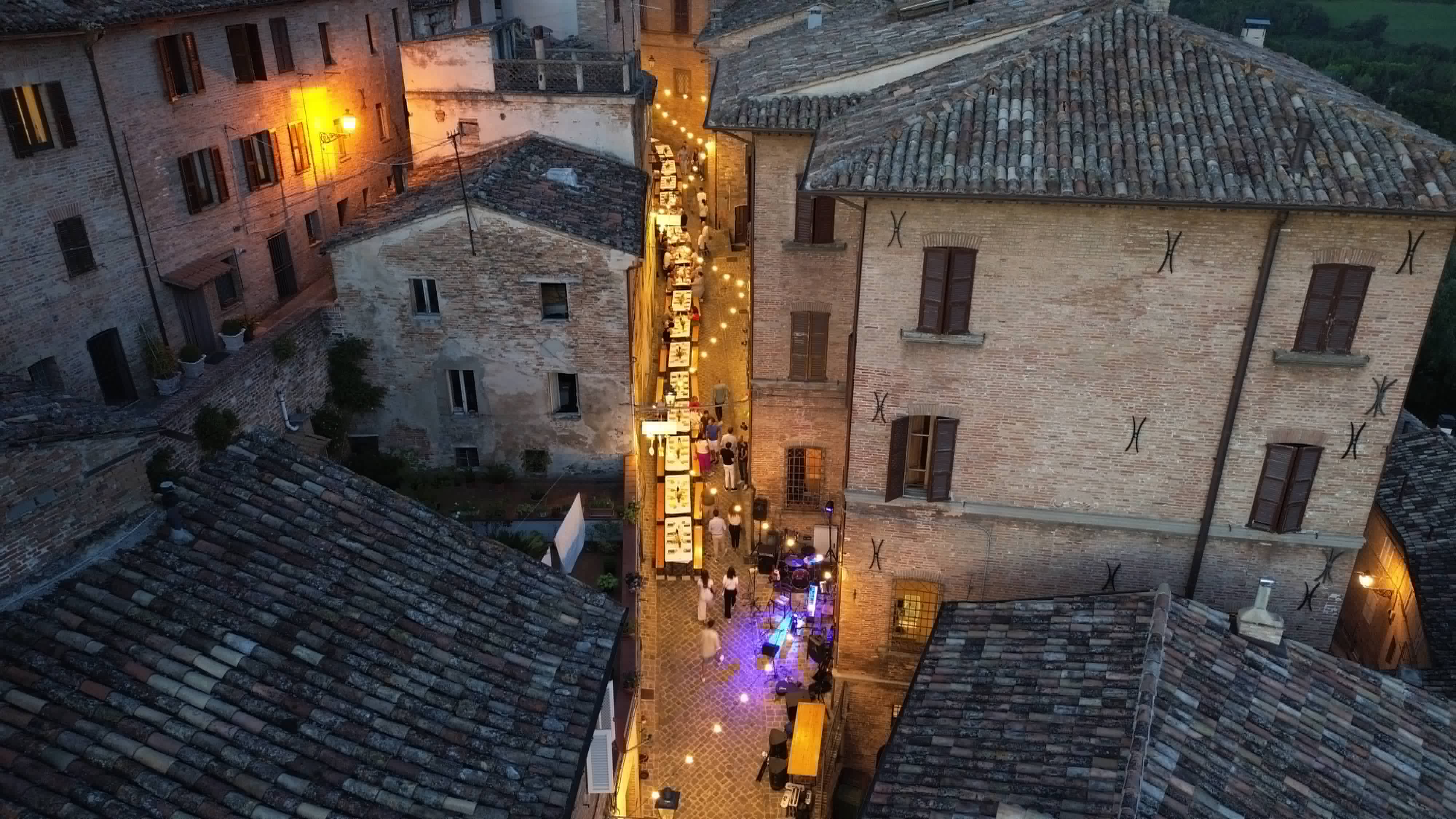Veduta dall'alto della lunga tavolata illuminata lungo il corso di Amandola al tramonto